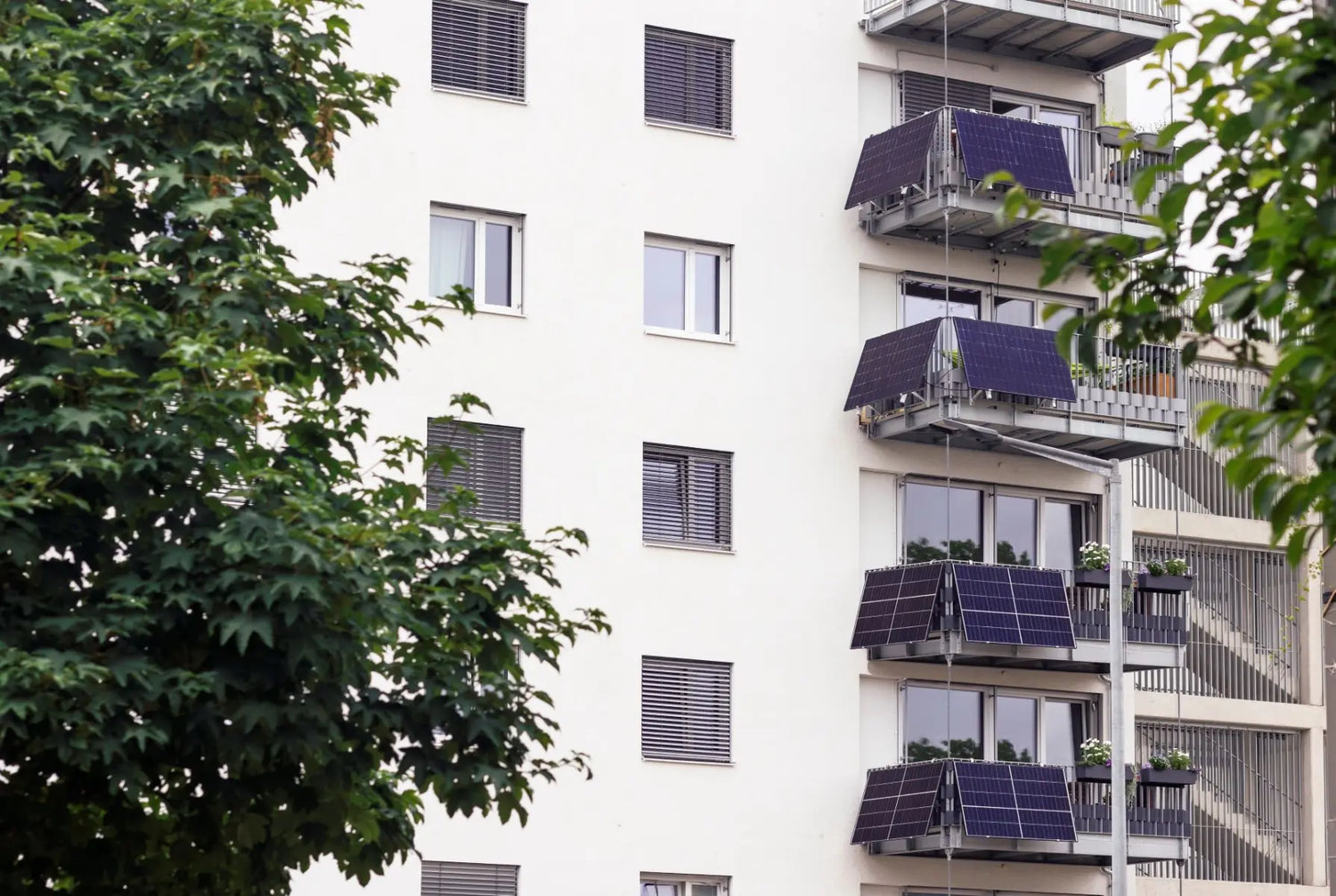 Modernes Mehrfamilienhaus mit Solaranlagen montiert an Balkongeländer