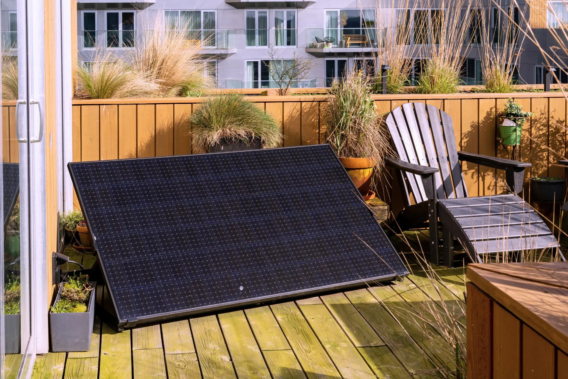 Solarmodul auf Flachdach mit Pflanzen und Wohngebäude im Hintergrund