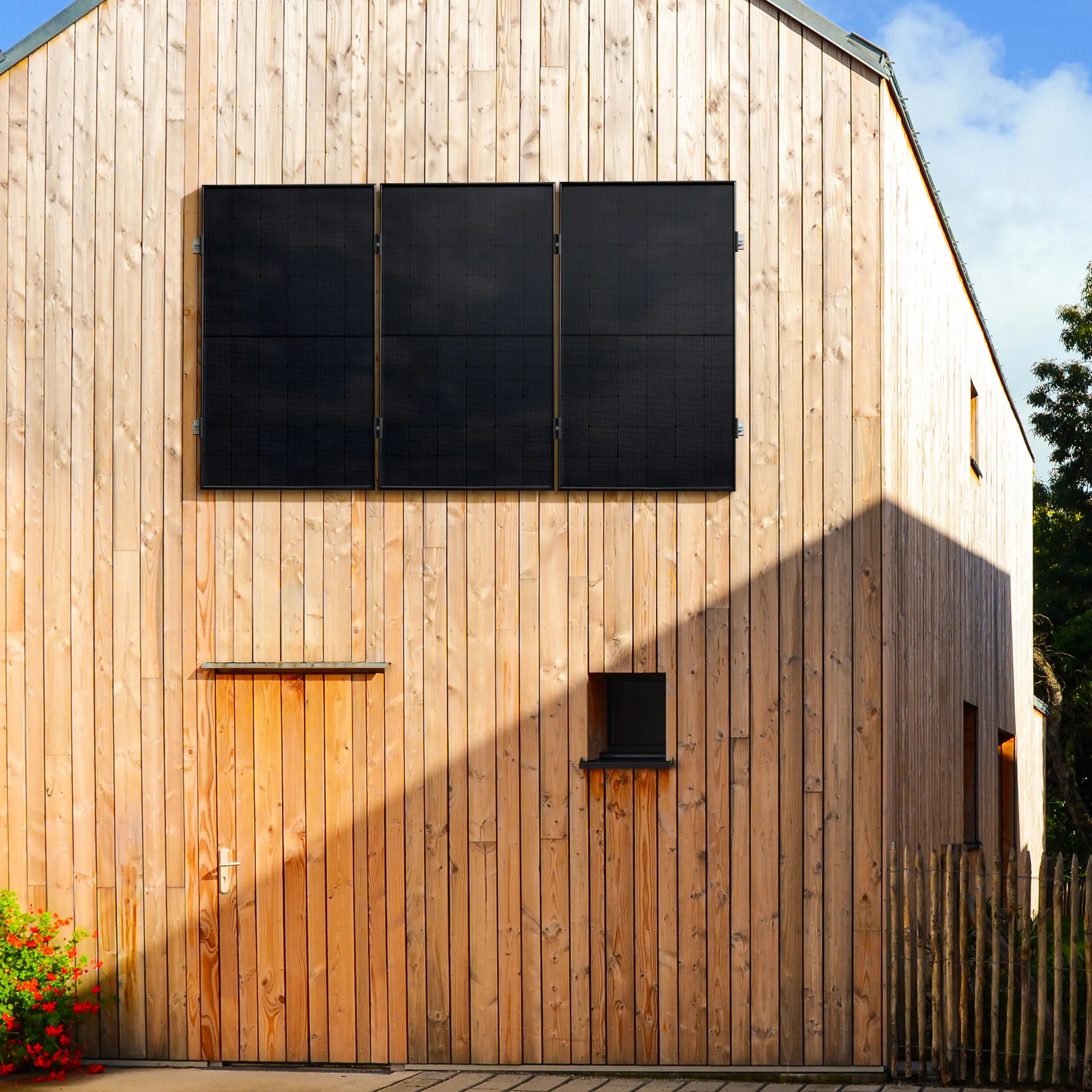 Holzfassade eines modernen Gebäudes mit 3 vertikal montierten Solarmodulen