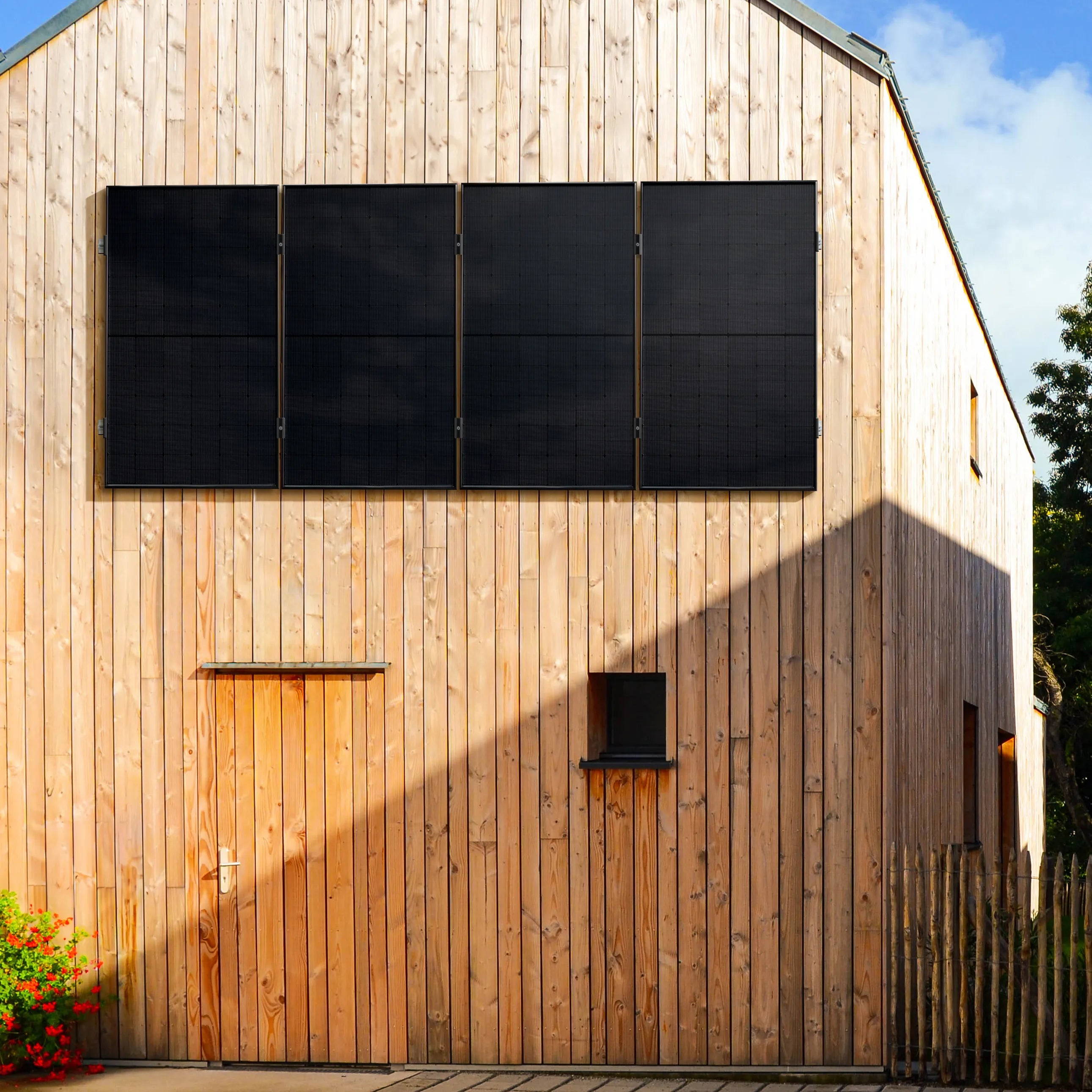 Holzverkleidete Hausfassade mit vier großen vertikal montierten Solarmodulen